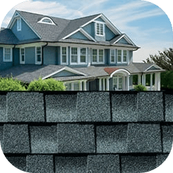 Charming blue house with large windows under a clear sky is overlaid by a close-up of grey asphalt shingles, highlighting roof detail and quality.