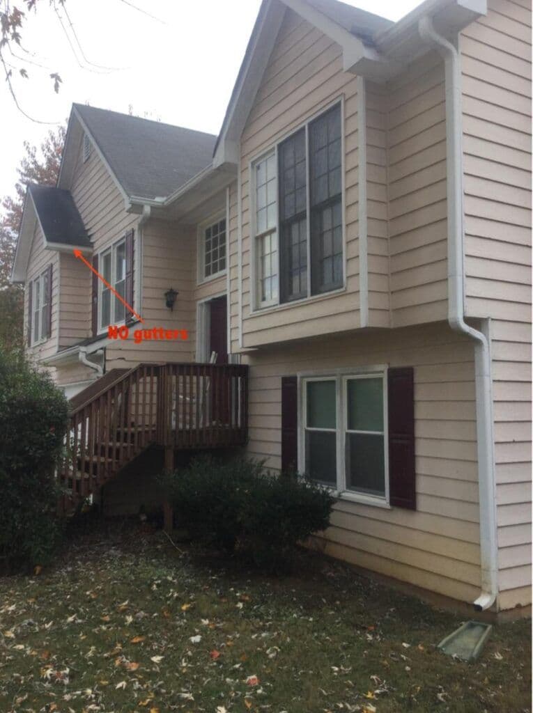 Tan two-story house with large windows and a small porch. An arrow points to missing gutters, marked "No gutters." Overcast sky, autumn leaves on grass.